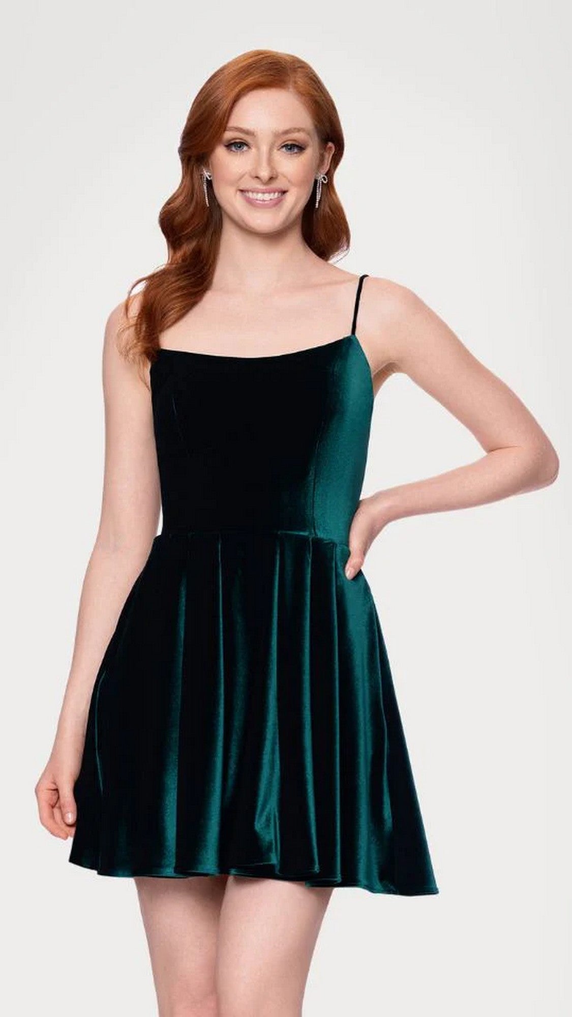 A woman with long red hair models the Blondie Nites 5601BN short prom dress in hunter—a sleeveless junior dress with thin straps and an a-line skirt—standing against a plain light background.